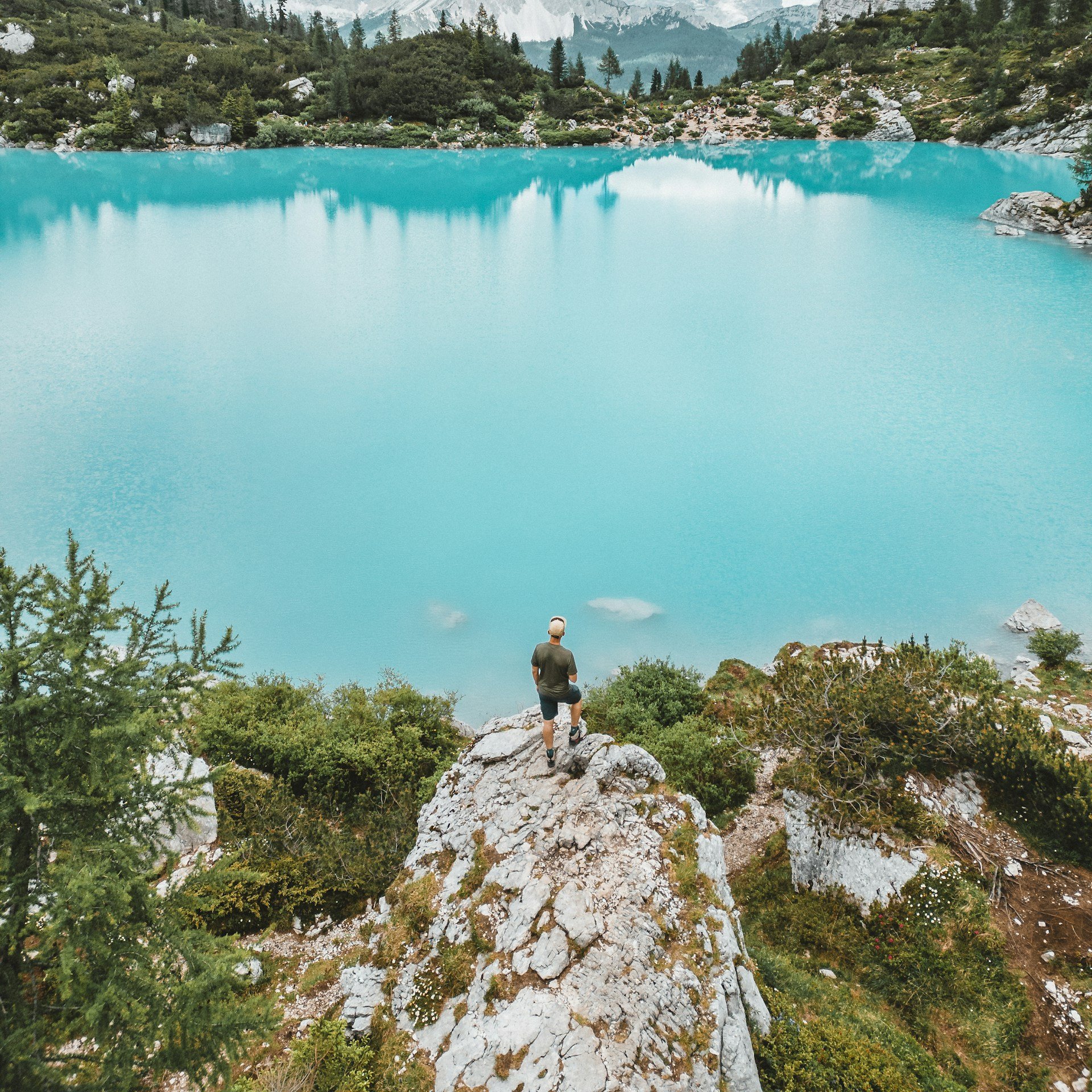 A hiker overlooking the turquoise water of Lake Sorapis in the Dolomites