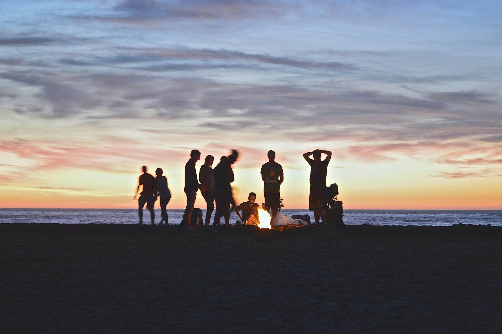 A group working together to build a campfire at sunset