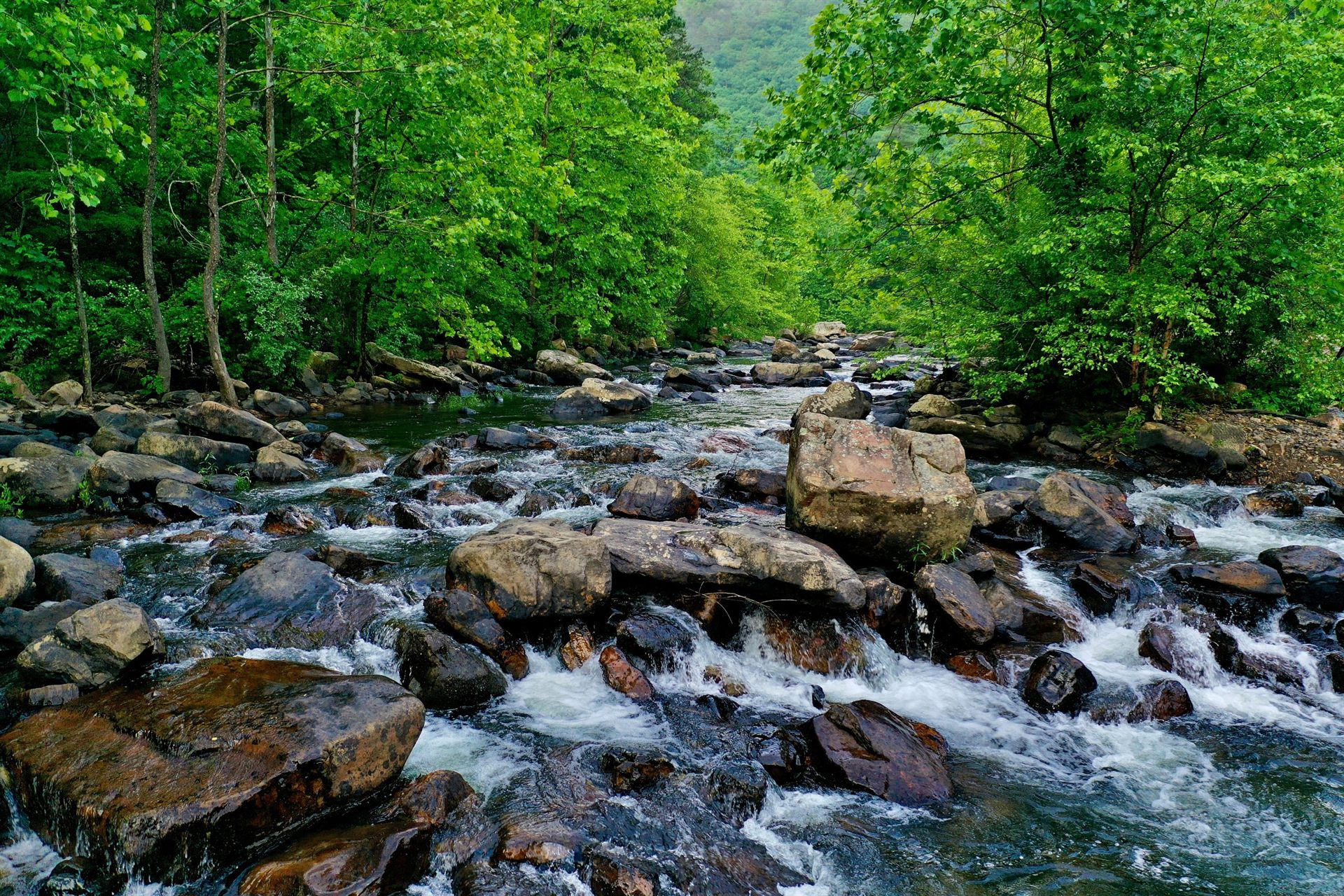 water flowing through gray rocks on river during daytime