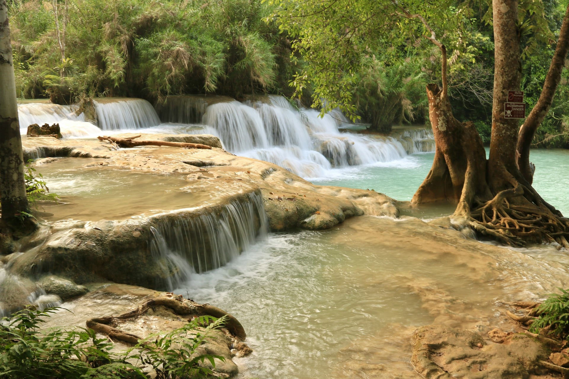 Turquoise water cascading through the forest at Kuang Si Falls in Laos
