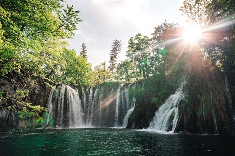 Sunlit waterfalls and turquoise water at Plitvice Lakes National Park in Croatia