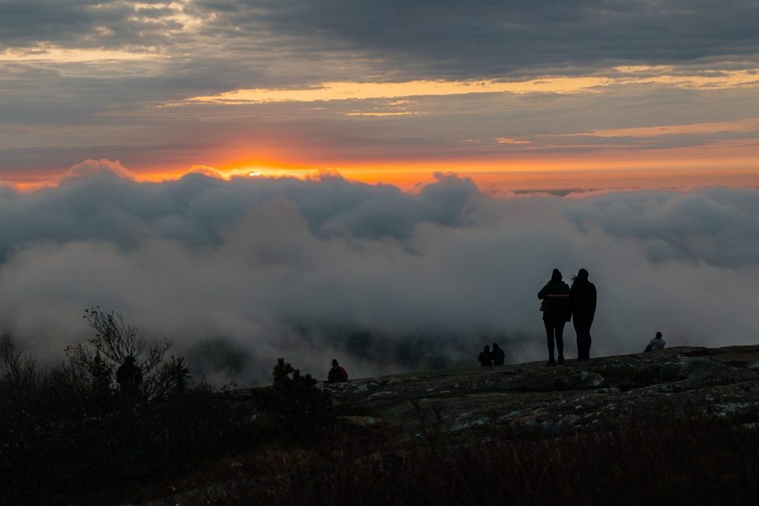 Hikers watching sunrise above the clouds from Cadillac Mountain in Acadia