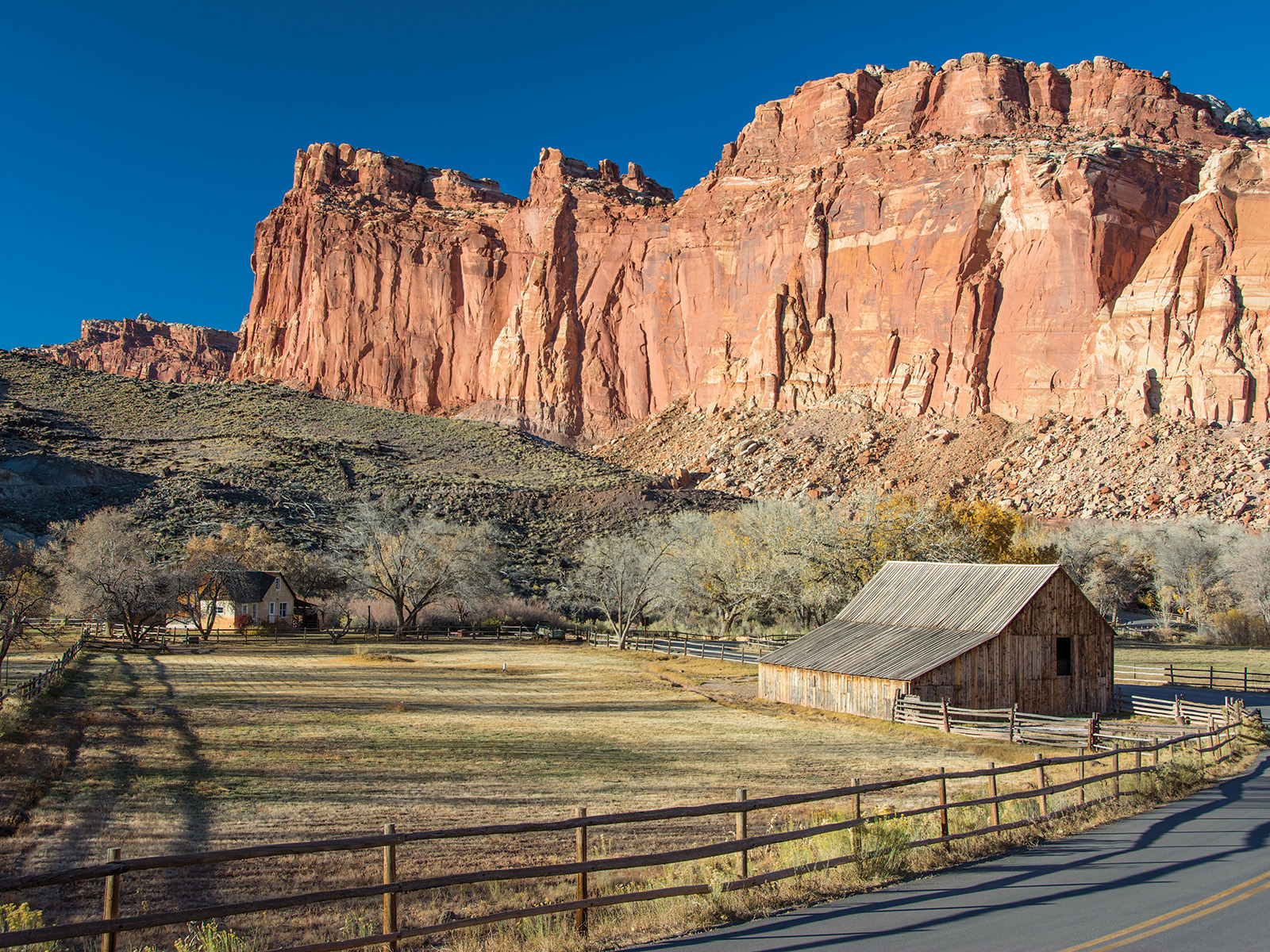 Historic Fruita farm buildings beneath Wingate Sandstone cliffs