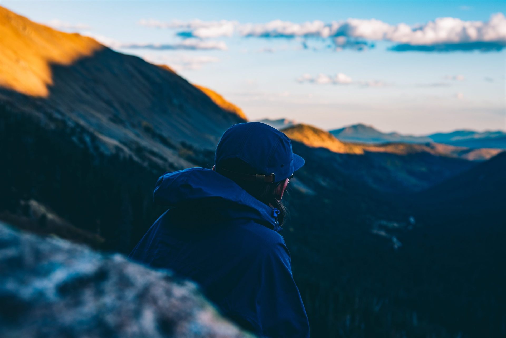 hiker with a hat watching the sunset from mountain range