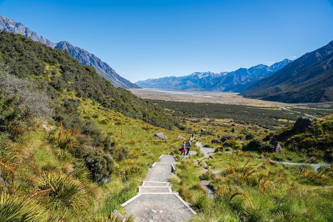 A backpacker following a mountain valley trail in New Zealand