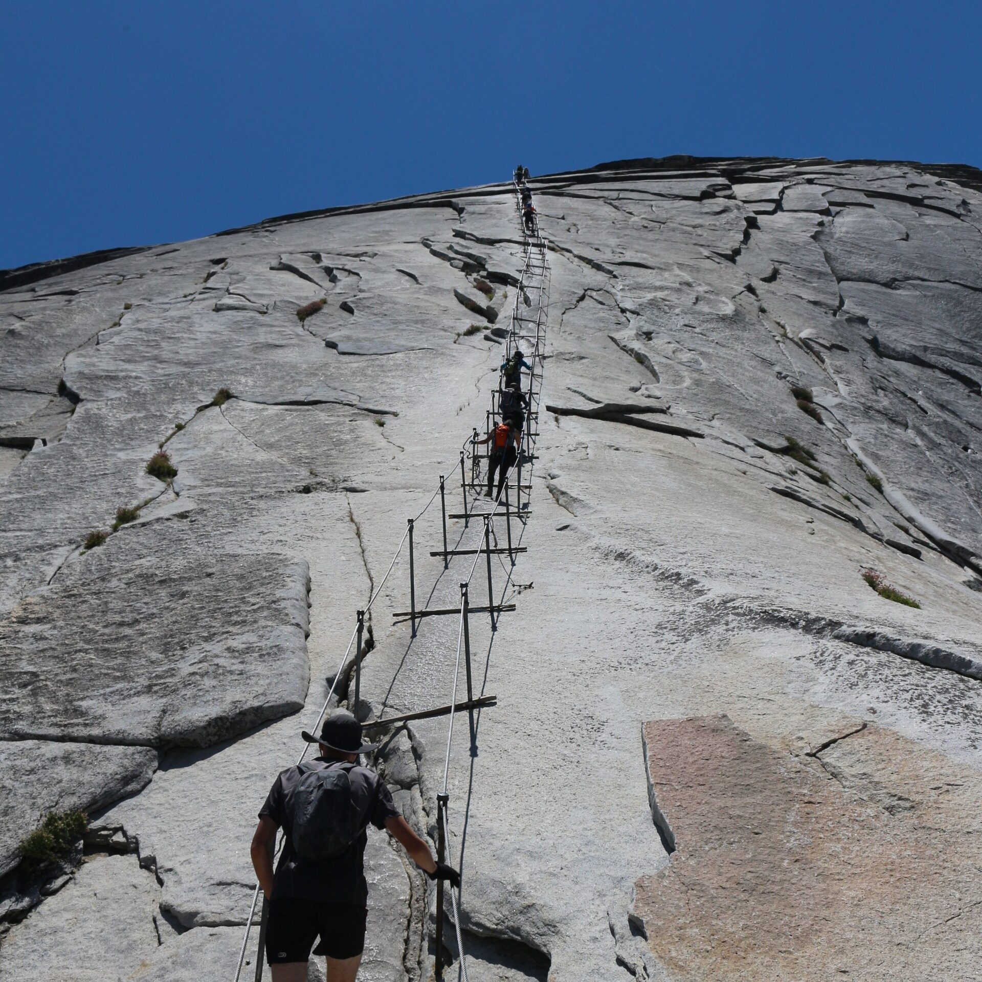 Hikers ascending the cables on Half Dome in Yosemite
