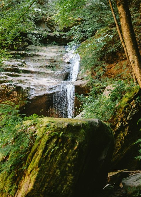 Forest waterfall surrounded by mossy rocks in Hocking Hills, Ohio