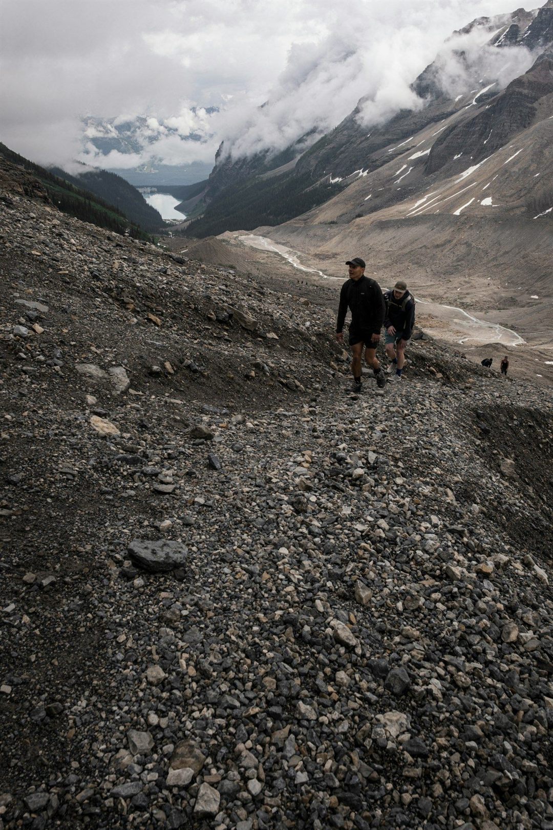 Hikers ascending a rocky trail above a mountain lake in the Canadian Rockies
