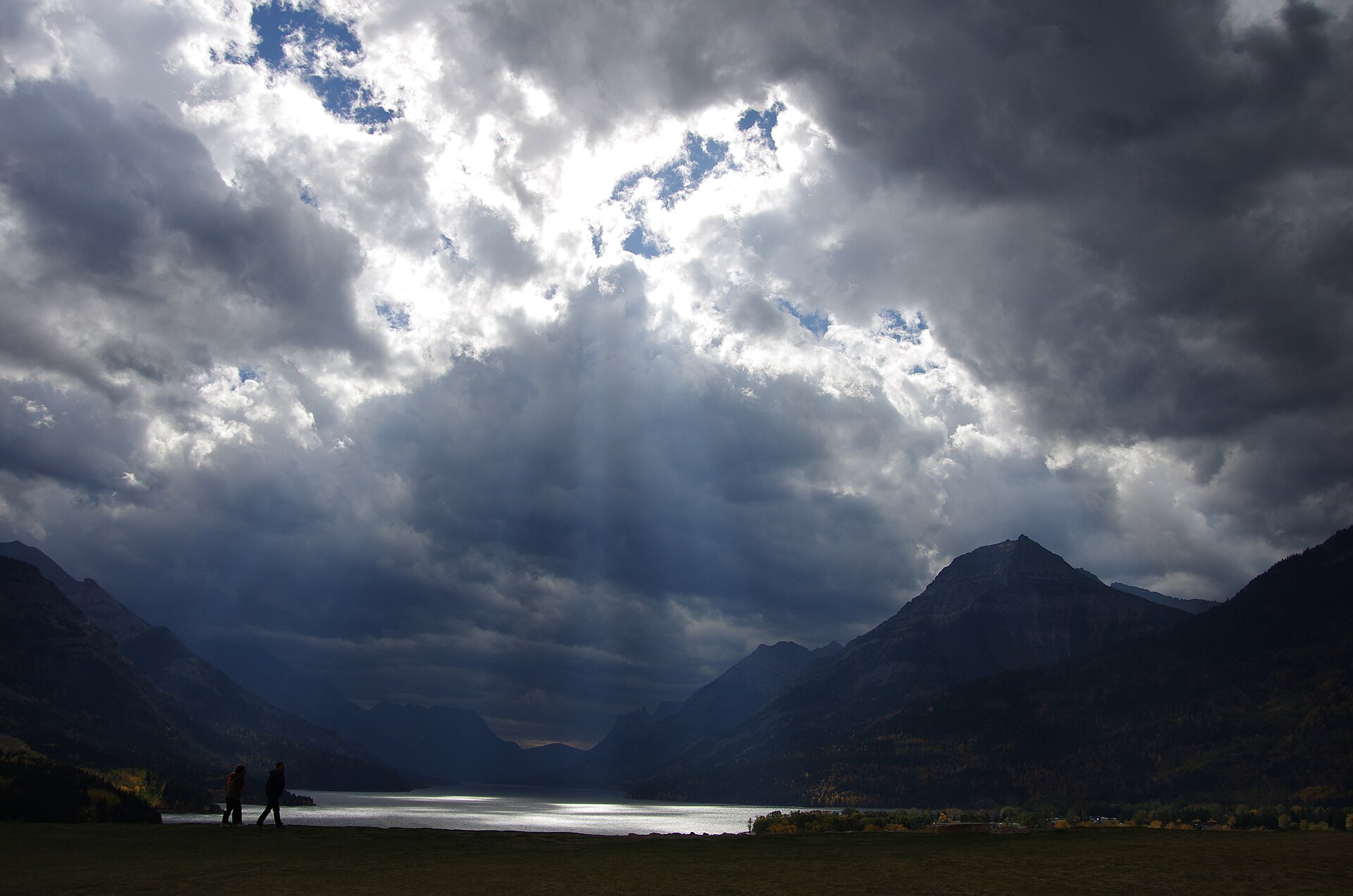 Sunlight breaking through clouds over Waterton Lake and the surrounding mountains
