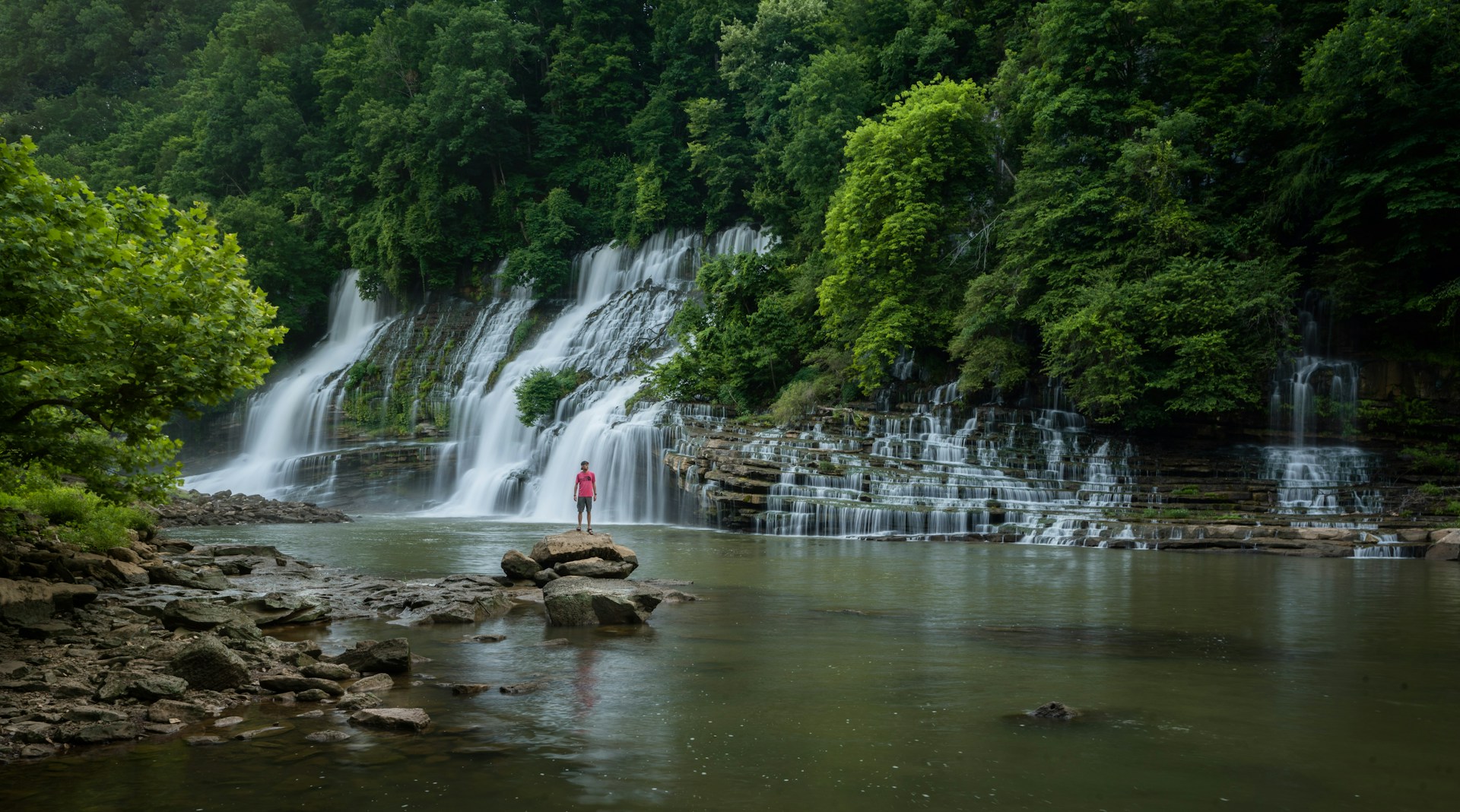 A hiker standing before a waterfall at Rock Island State Park