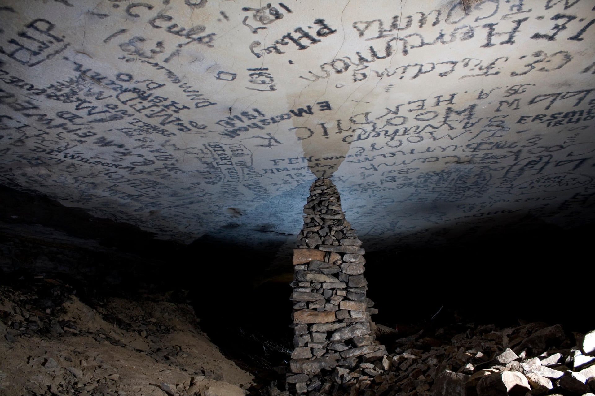 A historic stone pillar beneath the signature-covered cave ceiling
