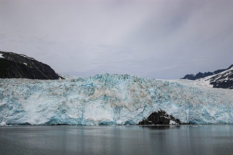 Glacier descending through mountains toward a fjord in Kenai Fjords National Park