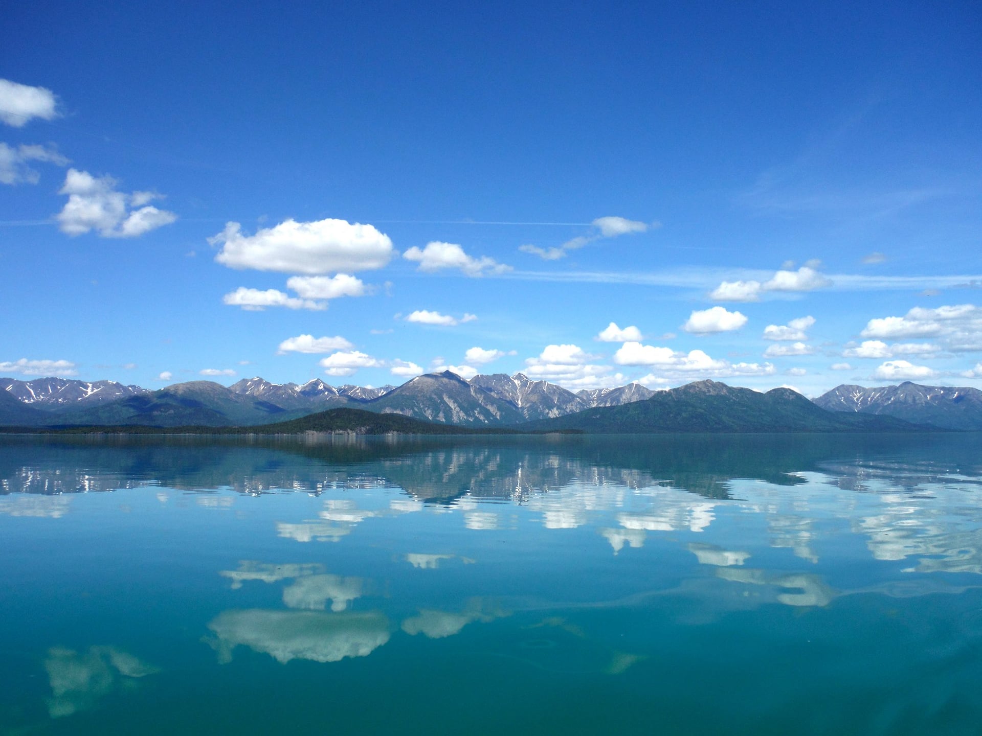 Mountains and clouds reflected in the calm water of Lake Clark