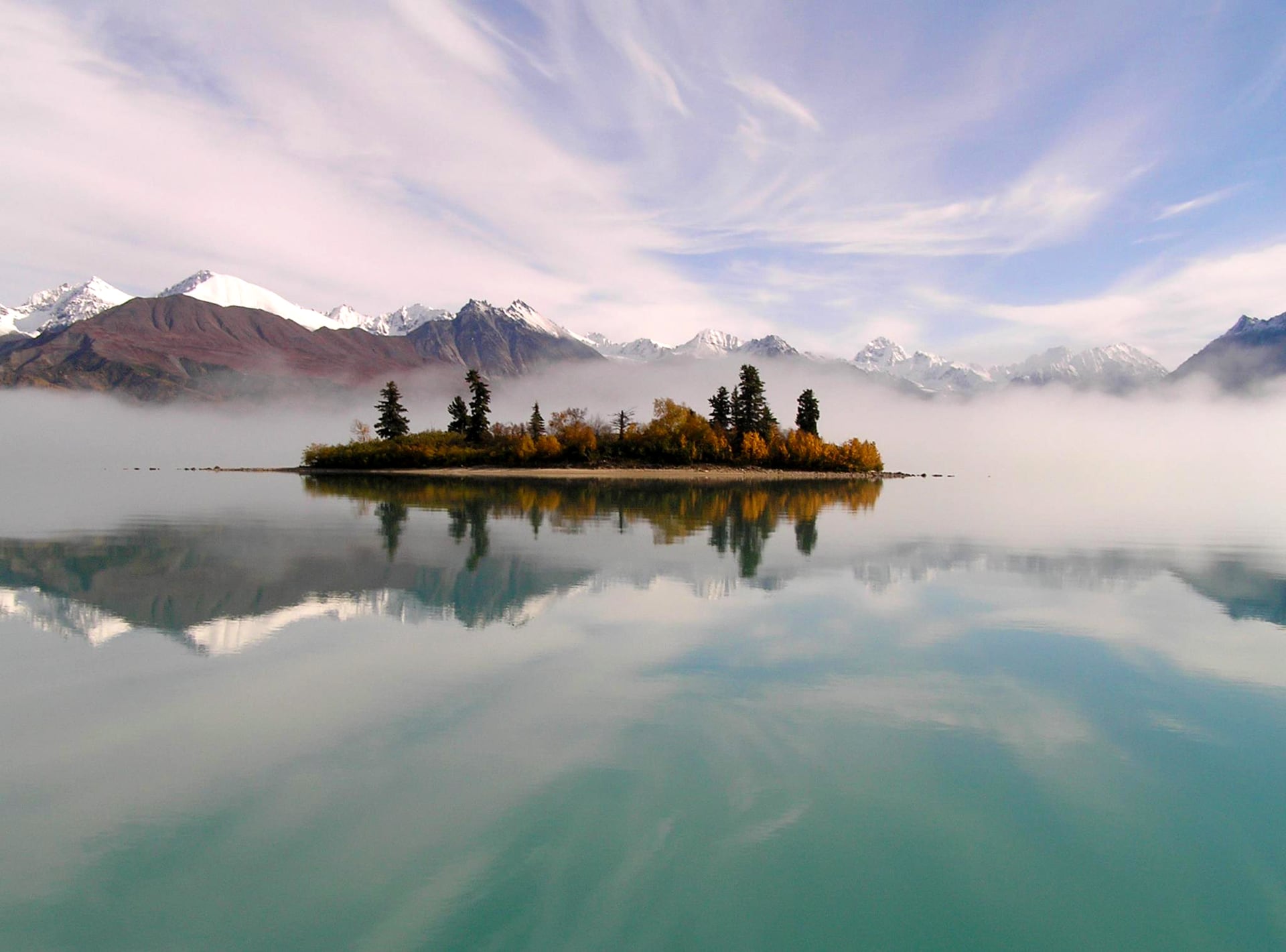 A turquoise glacier-fed lake reflecting mountains and evening sky