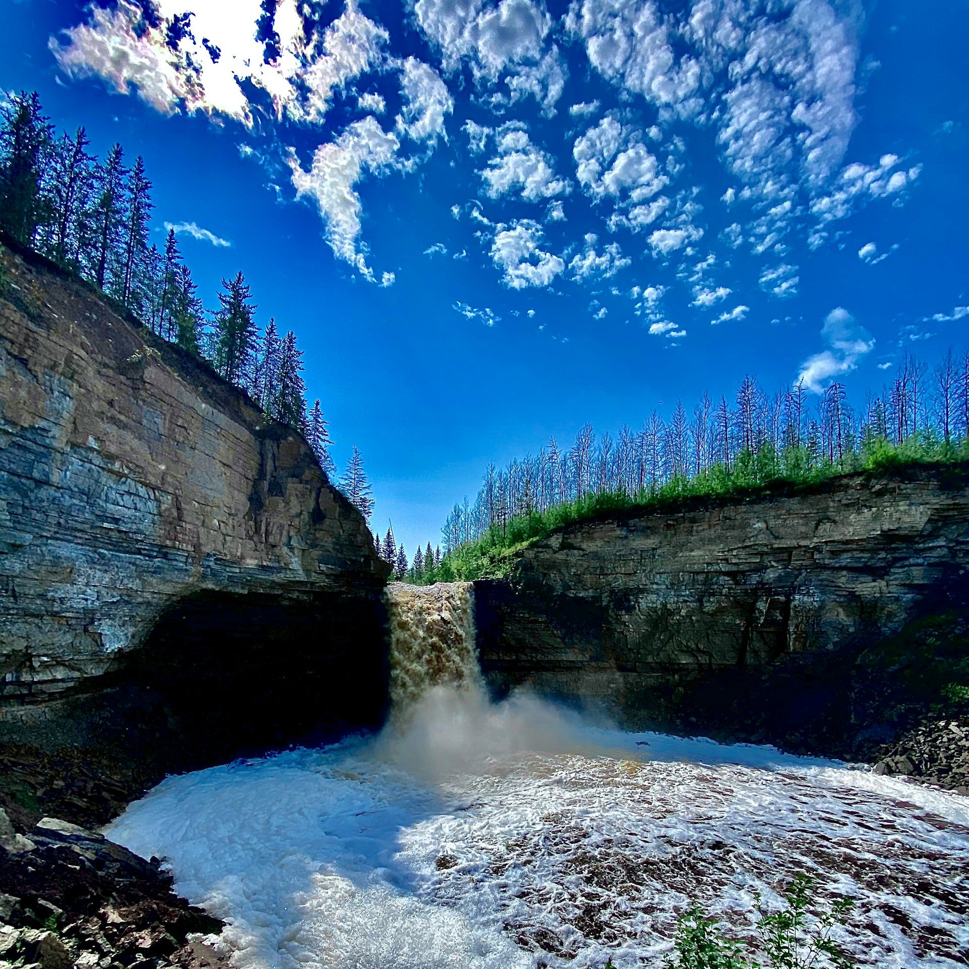 A broad waterfall flowing over layered rock in Wood Buffalo National Park