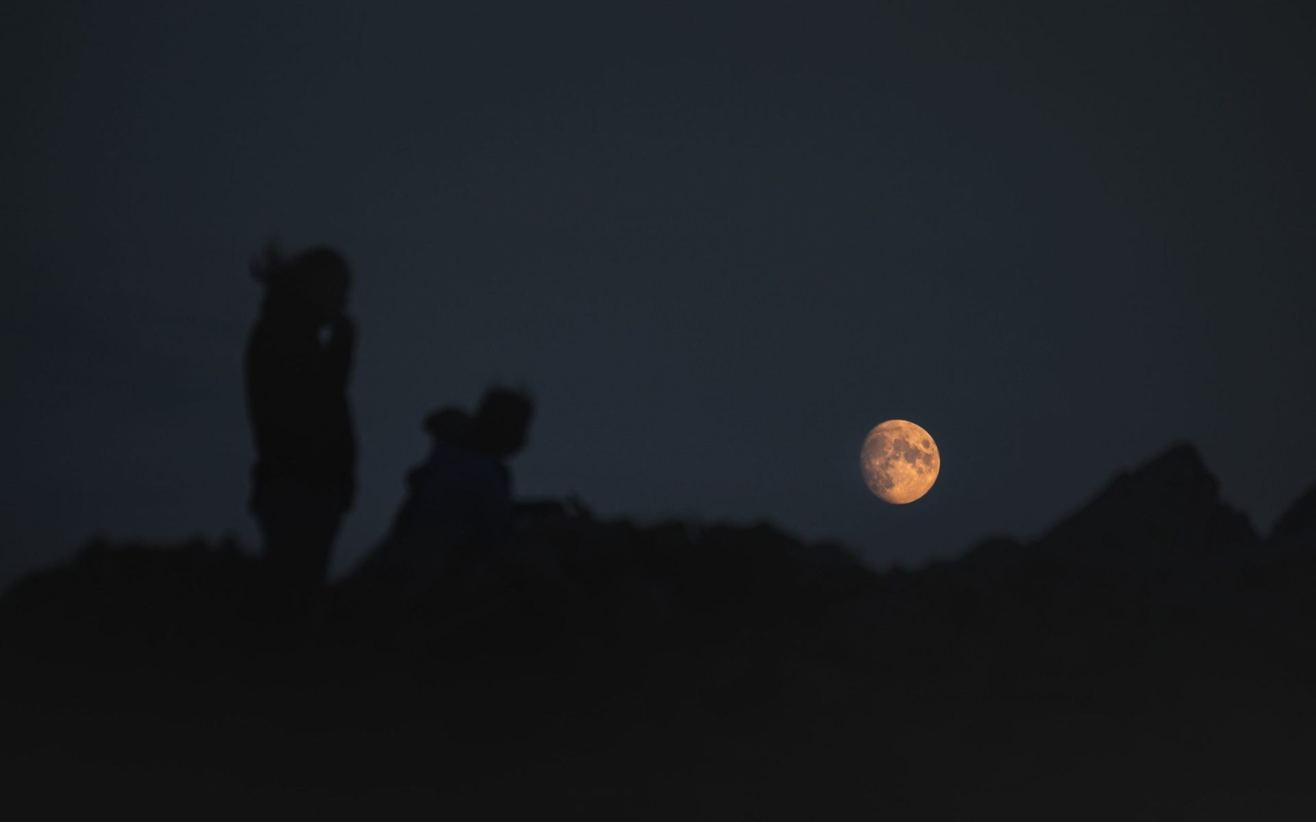 hikers looking at moonrise at night