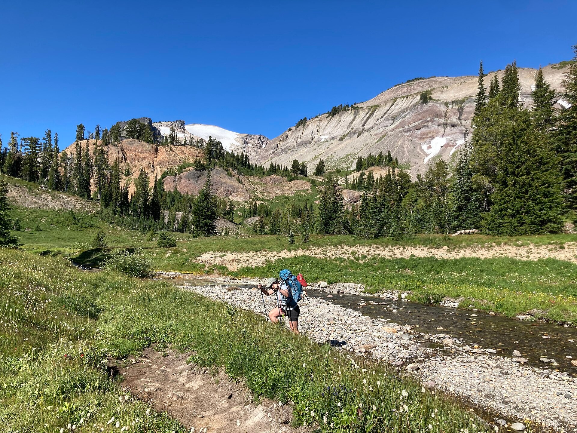 A backpacker choosing a route through a rocky stream