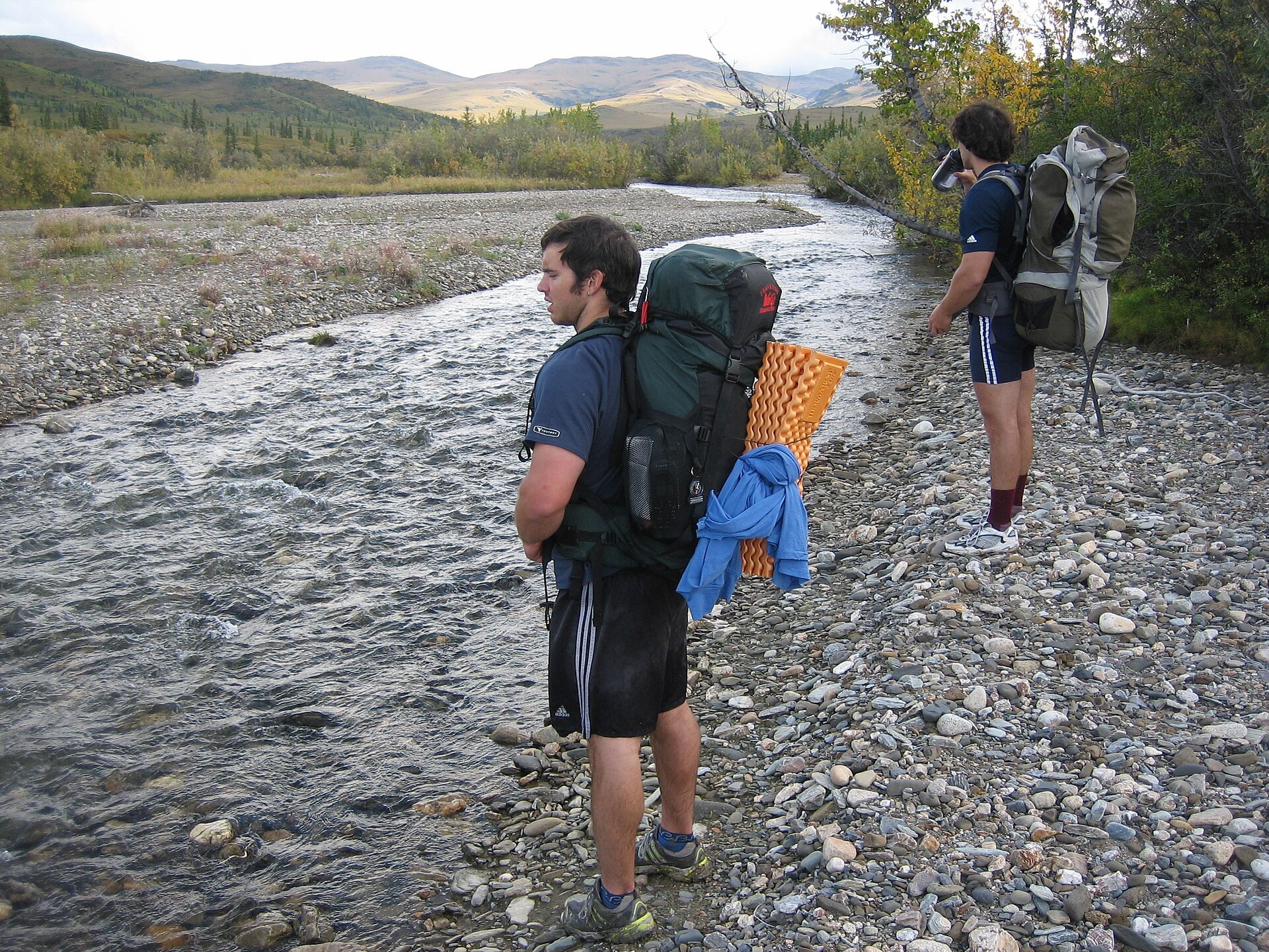 Backpackers traveling beside a braided wilderness river