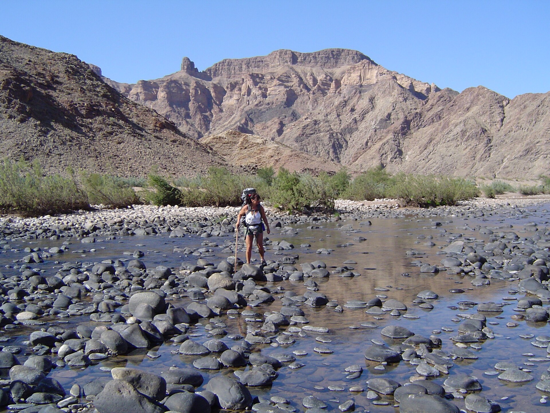 A hiker testing a shallow river crossing