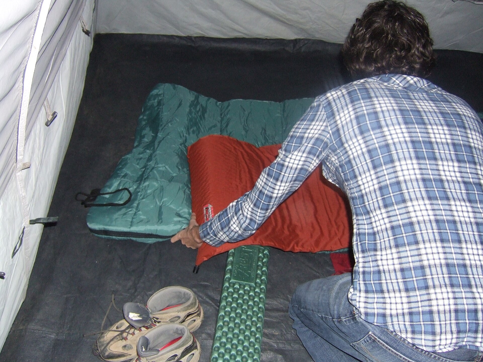 A camper adjusting a sleeping bag inside a tent
