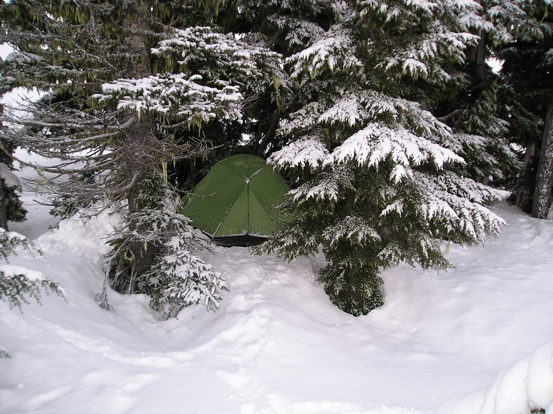A backcountry tent pitched in deep winter snow
