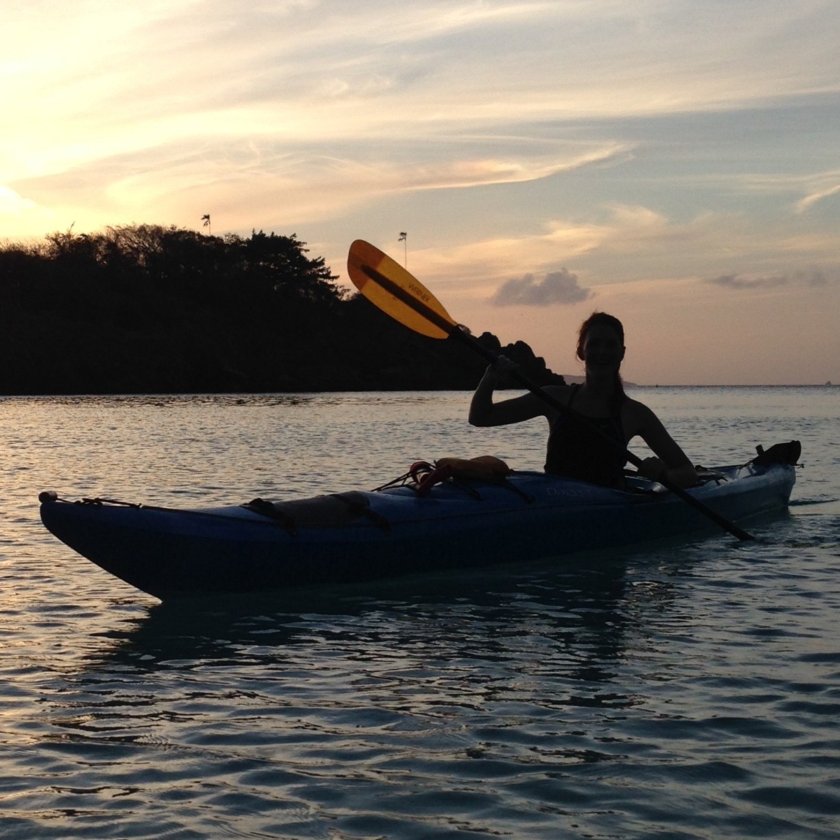 A kayaker paddling near St. John at sunset